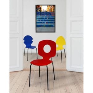 Trois chaises Tsé Tsé en bois multiplis moulé, une chaise est rouge, l'autre est bleu et la dernière est jaune. Sur le mur du fond, on voit une photo d'une rue.