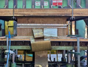 Photo d'une presse poisson matrice en train de mouler une pièce de bois moulé